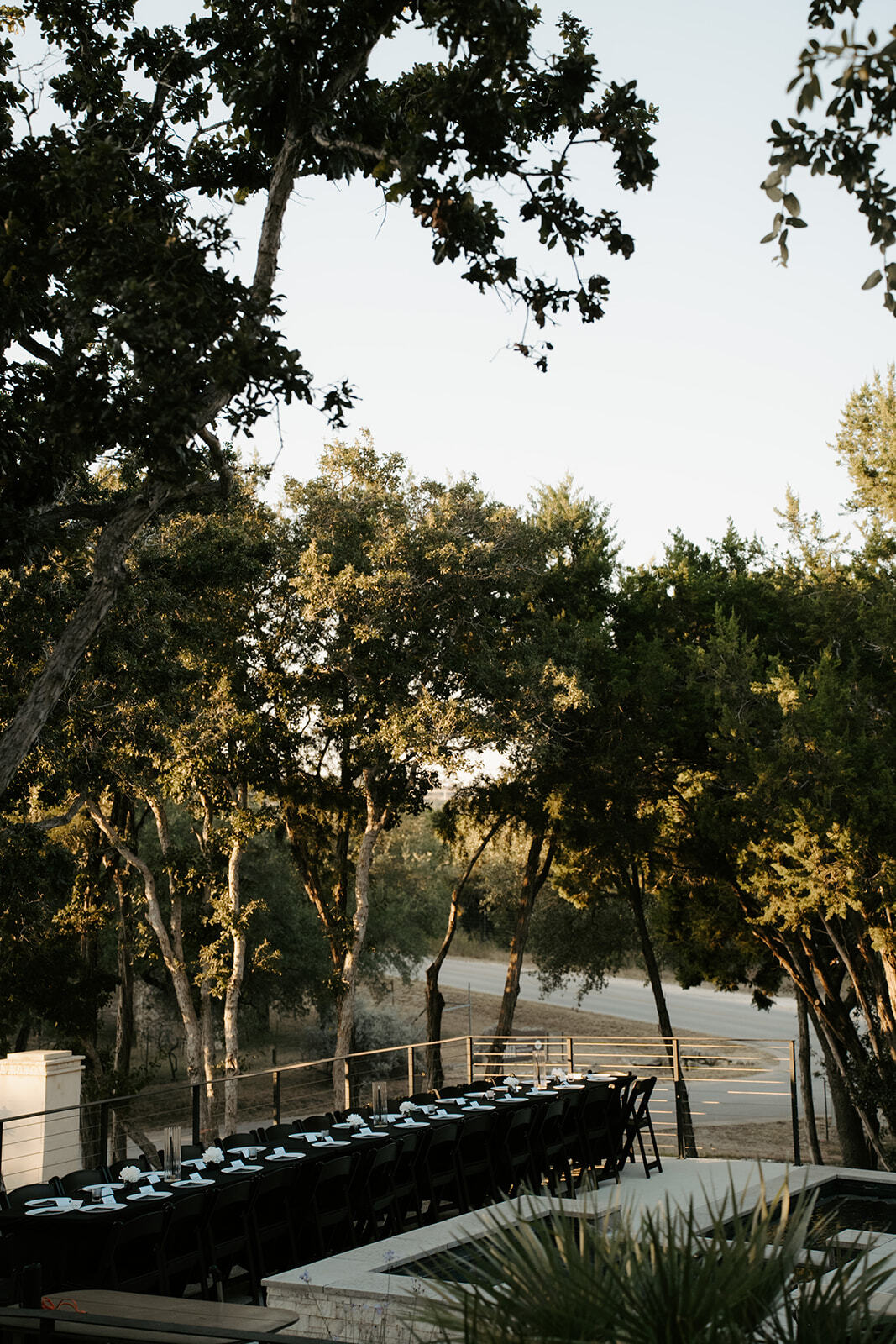 Long dinner table set beneath the oak trees at Las Luces Village
